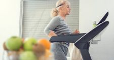 Elderly lady walking on the treadmill in her home.